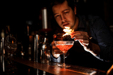 Young bartender making a fresh cocktail with a smoky note