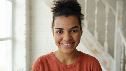 Closeup portrait of beautiful african american girl laughing and looking into camera at home indoors