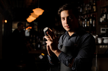 Barman holding a shaker in a dark bar