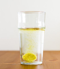 Effervescent tablet and glass of water. Vitamin beverage.