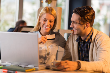 Shot of beautiful  young couple paying bills online at cafe