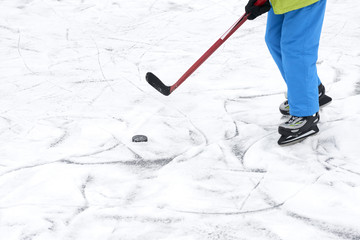 Outdoor Ice skating. Hockey player's legs and skates on ice rink.
