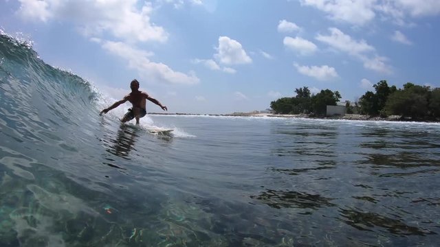 Surfer rides crystal clear ocean wave at sunny day
