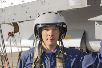 Military pilot in helmet stands near jet plane
