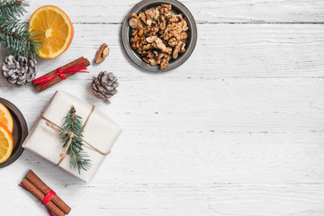 Orange in the cut, cinnamon, walnut on a white background. Branches of Christmas trees, gifts and bumps. A flat place, a place to copy, a top view. Holidays.