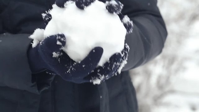 Woman makes snowball at winter snowy day outside.