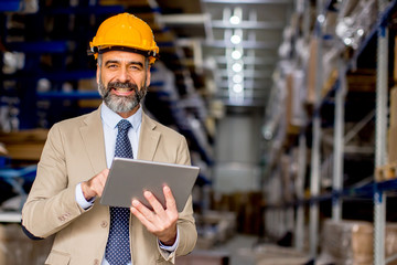 Mature engineer in the warehouse with digital tablet