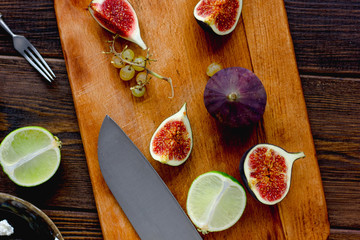 Kitchen board with knife and pieces of fig fruits on it.
