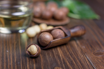 Macadamia nuts in a wooden scoop over the dark table.