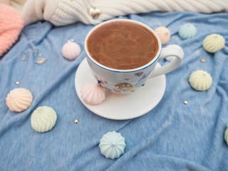 Cup of cocoa with foam and multi-colored bise on a wooden table