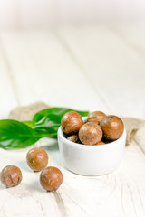 White ceramic bowl with macadamia nuts over the wooden table.