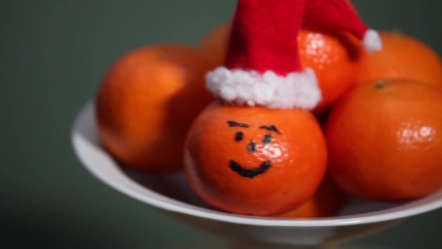 bowl of oranges, fruit orange in Santa hat in the foreground