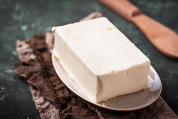 Fresh butter and knife on concrete background