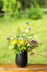 bouquet of wildflowers and strawberry berries stand on the terrace