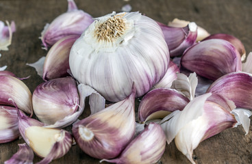 Closeup of spices, showing purple whole garlic bulbs, garlic cloves, on top of a wooden surface, top view