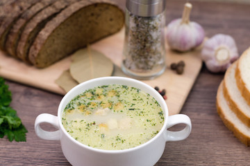 Mushroom soup with croutons in a white dish is on a wooden table.
