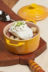 Corned beef and poached egg /  Freshly baked corned beef and poached egg with horseradish in a yellow mini cast-iron pot and top with sliced chives on a wood serving board with an artisan spoon