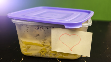 Open plastic container with lunch and heart on a piece of paper concept of eating at work