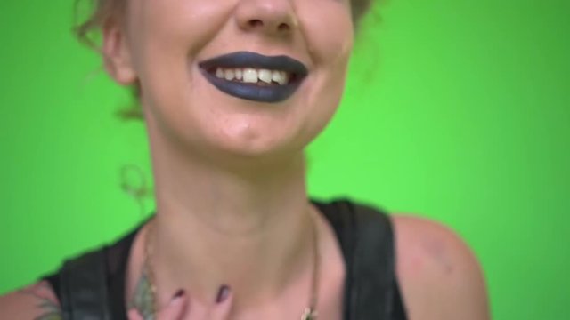 Beautiful caucasian young woman with black lipstick dancing, smiling and laughing at camera on green screen background
