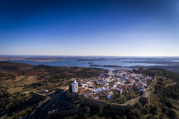 Aerial view of the historic village of Monsaraz in Alentejo with the Alqueva dam reservoir on the background; Concept for travel in Portugal and Alentejo