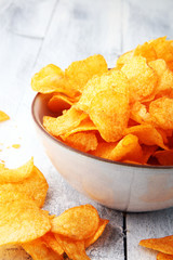 Crispy potato chips. Paprika chips on white wooden background