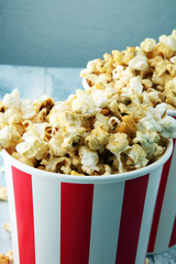Paper cup in red and white with popcorn on wooden background