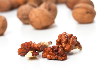 split walnut and whole walnut in the background (out of focus) on a white background, isolated