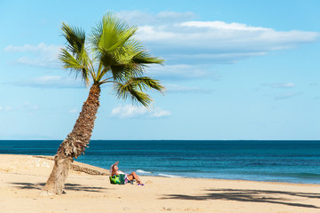 Woman under the palm tree on the beach