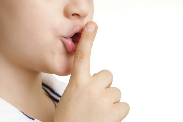 Studio shot of young boy with finger on lips - silent gesture