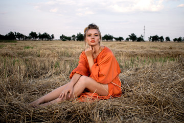 Beautiful woman  with beautiful legs in the field on a hay looking at you