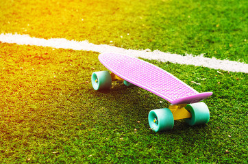 penny board on the grass. sports lifestyle. Sun rays