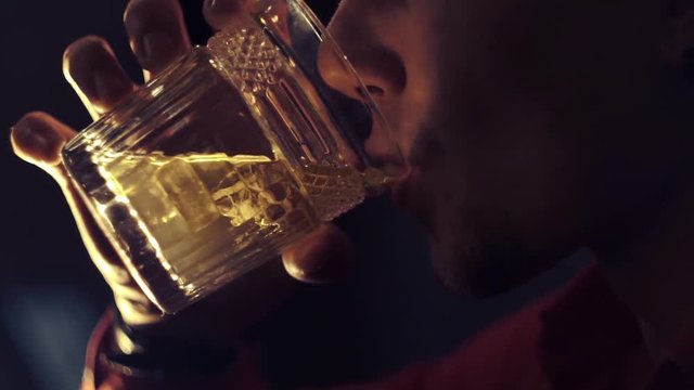 Man in a red shirt is drinking whiskey at the bar