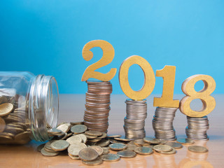 2018 New year saving money and financial planning concept. Gold wooden number 2018 on stack of...