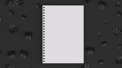 Blank spiral notebook with black binder clips on black table