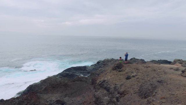 Couple is making pictures of foamy sea from cliff