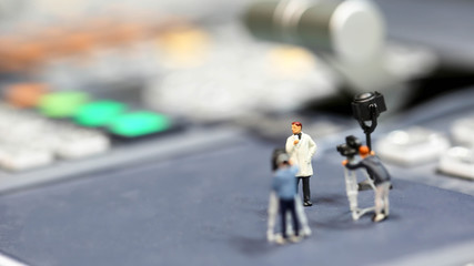 Miniature people : journalists , cameraman ,Videographer at work shooting on switcher control of Television Broadcast,color buttons