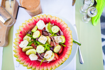 Delicious fresh greek salad served for lunch at outdoor restaurant with beautiful view on the sea and port