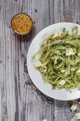 spaghetti with spinach green with mozzarella, herbs and French mustard on a white plate on a light wooden table