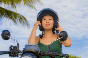 Fototapeta premium young pretty happy and cute Asian Chinese woman adjusting motorcycle helmet riding on scooter motorbike isolated on a blue sky in safety concept