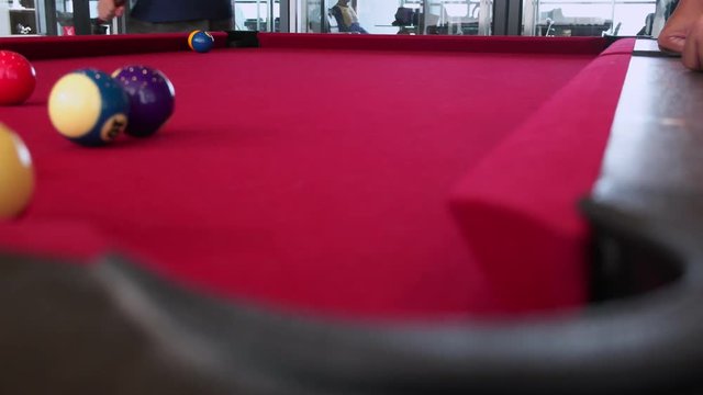 Playing the pool-billiard game on red baize table. This is sports.