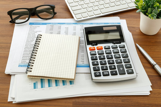 Financial accounting with calculator and blank notebook on wooden table