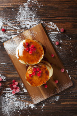 syrups with powdered sugar on a wooden cutting board, a sieve of a viburnum berry and caramel topping on a dark wooden table