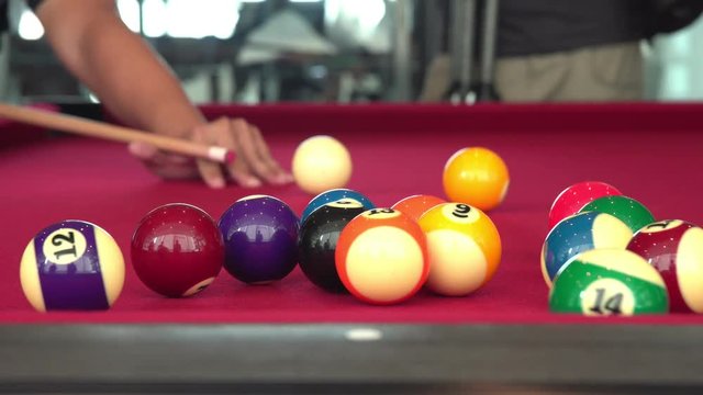 Playing the pool-billiard game on red baize table. This is sports.