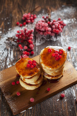 syrups with powdered sugar on a wooden cutting board, a sieve of a viburnum berry and caramel topping on a dark wooden table