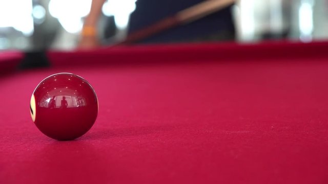 Playing the pool-billiard game on red baize table. This is sports.
