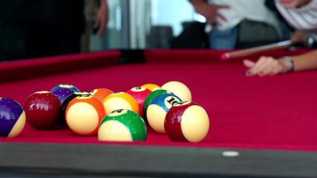 Playing the pool-billiard game on red baize table. This is sports.