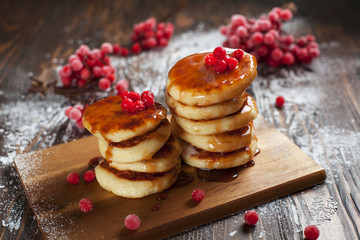 syrups with powdered sugar on a wooden cutting board, a sieve of a viburnum berry and caramel topping on a dark wooden table