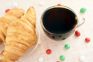 Big croissant. Multicolored candy. Hot tea