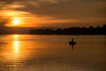 Naklejka na ściany i meble Fishing on a boat at sunset