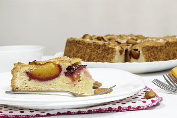 Homemade pie with almond frangipan and organic plums on white plate.